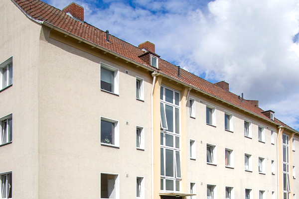Ein beiges Haus angeschnitten mit blauem Himmel und weißen Wolken