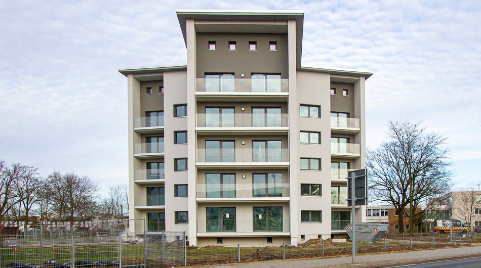Ein schickes Haus mit Flachdach und einer Balkonfront aus Glas und Bodentiefen Fenstern